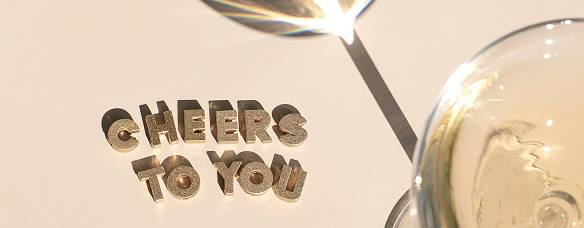 a flat lay image of a champagne coupe reflecting its shadow with "cheers to you" written out in sparkly gold letters | 12 Tips To Incorporate New Wellness Rituals In The New Year | Sugar Magnolia