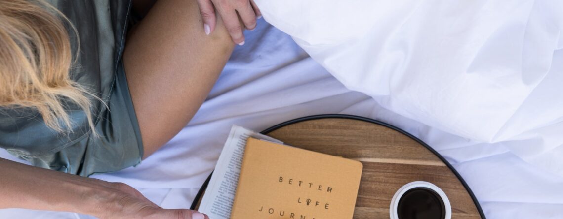 A woman sitting in bed with a tray of coffee, pastries, and a journal. | Little Rituals for Big Peace: Embracing the Sugar Magnolia Ethos - Sugar Magnolia