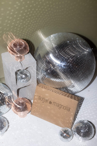 Sugar Magnolia New Year gift box display with disco balls and sparkling lights.