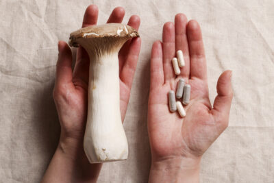 Two hands holding a mushroom and microdosing capsules, symbolising microdosing vs. macrodosing comparison