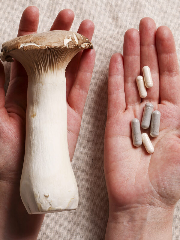 Two hands holding a mushroom and microdosing capsules, symbolising microdosing vs. macrodosing comparison