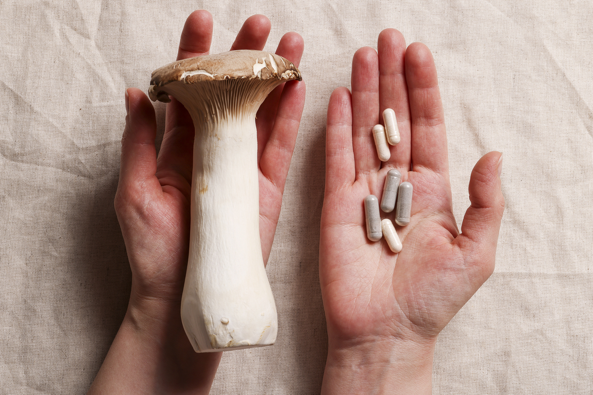 Two hands holding a mushroom and microdosing capsules, symbolising microdosing vs. macrodosing comparison