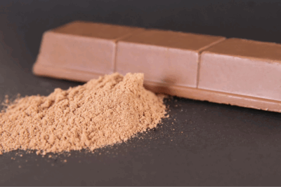 Cocoa powder and milk chocolate bar on a dark background