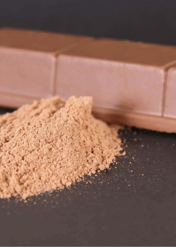 Cocoa powder and milk chocolate bar on a dark background